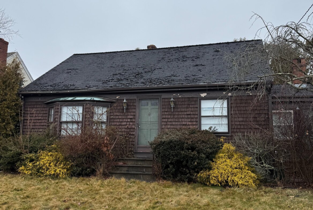 Brown shingled cape with a worn roof in southeastern Massachusetts
