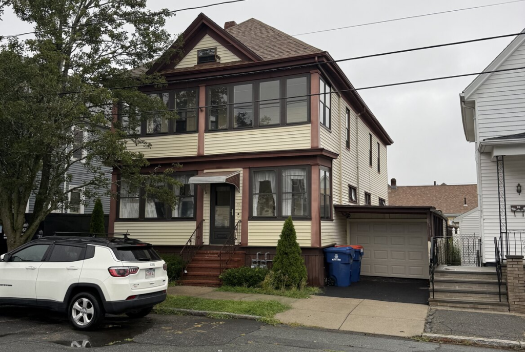 Cream three family house with an enclosed porch in southeastern Massachusetts