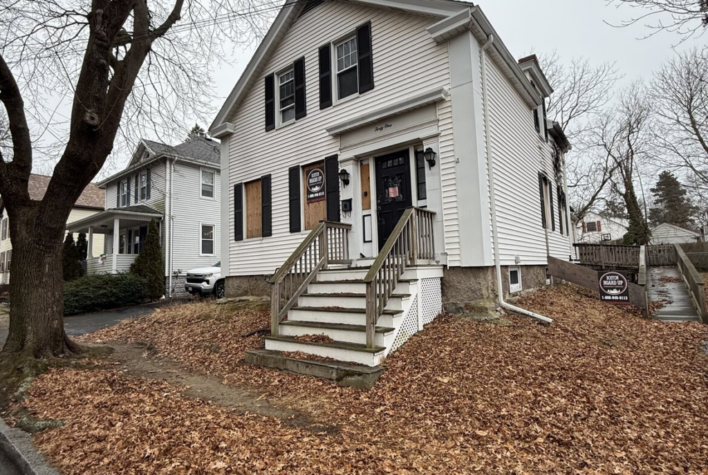 White colonial with boarded first floor windows in southeastern Massachusetts